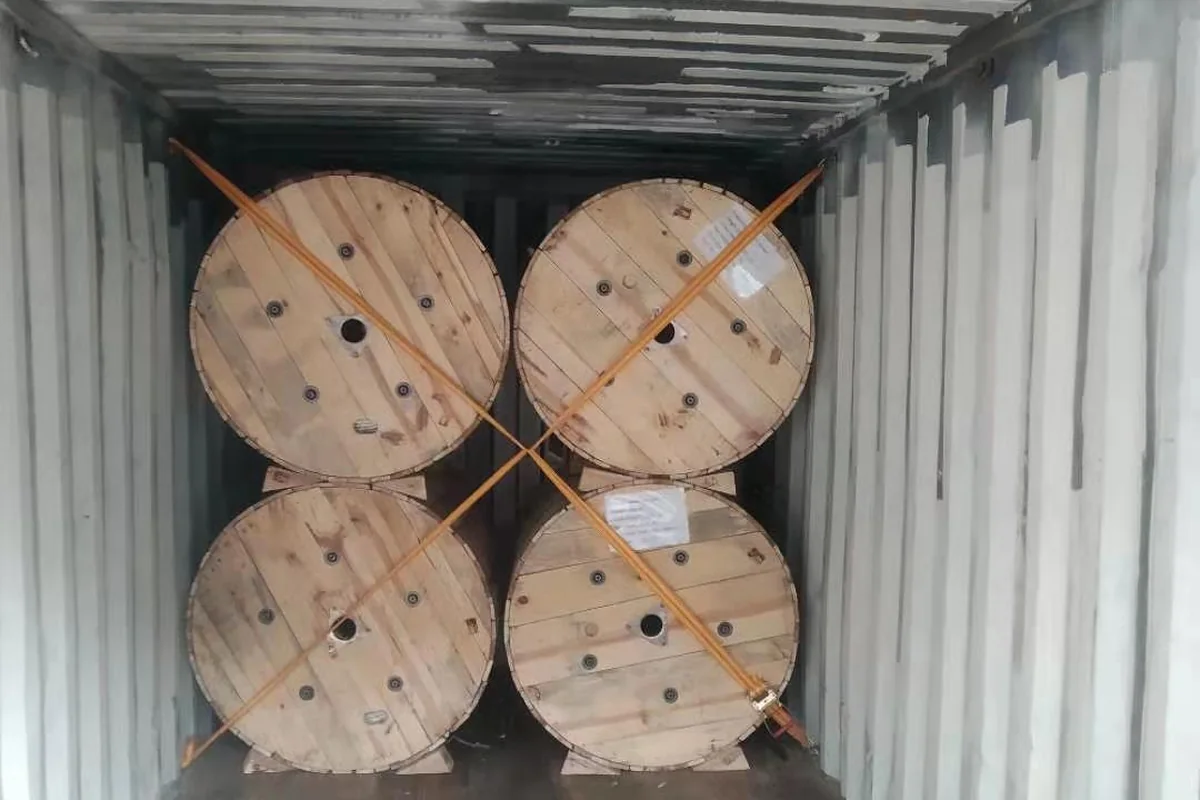 Wooden drums of overhead conductors loaded into shipping container